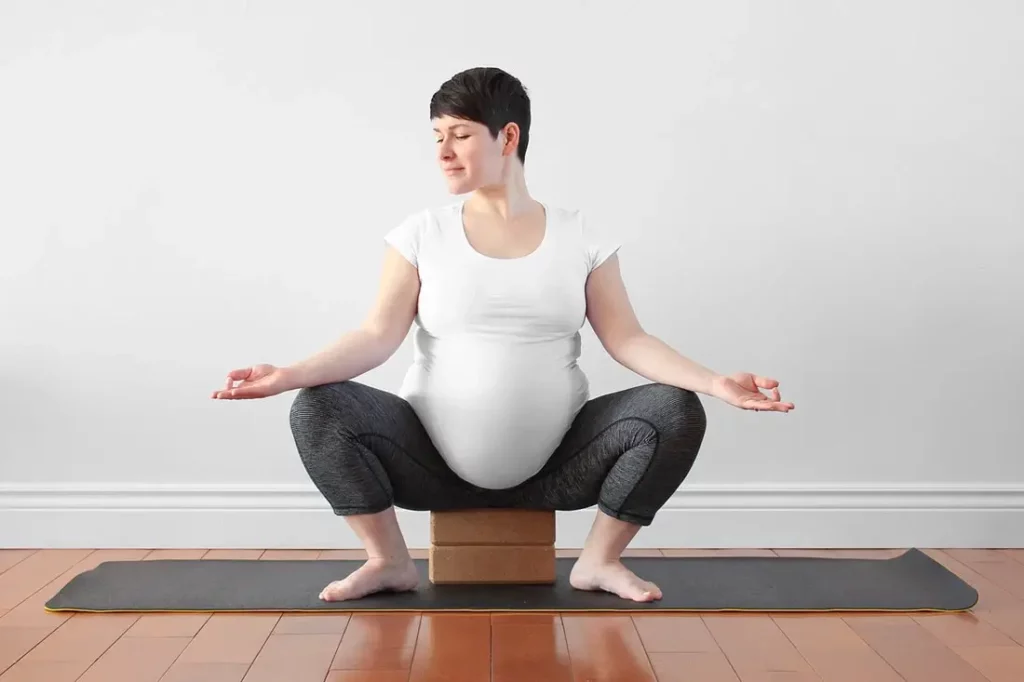 Mother on blocks doing malasana yoga position