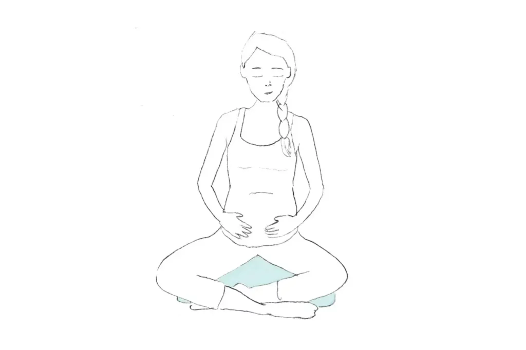 Pregnant woman sitting crossed legged doing belly breathing drawing