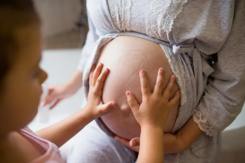 daughter touching mothers pregnant belly