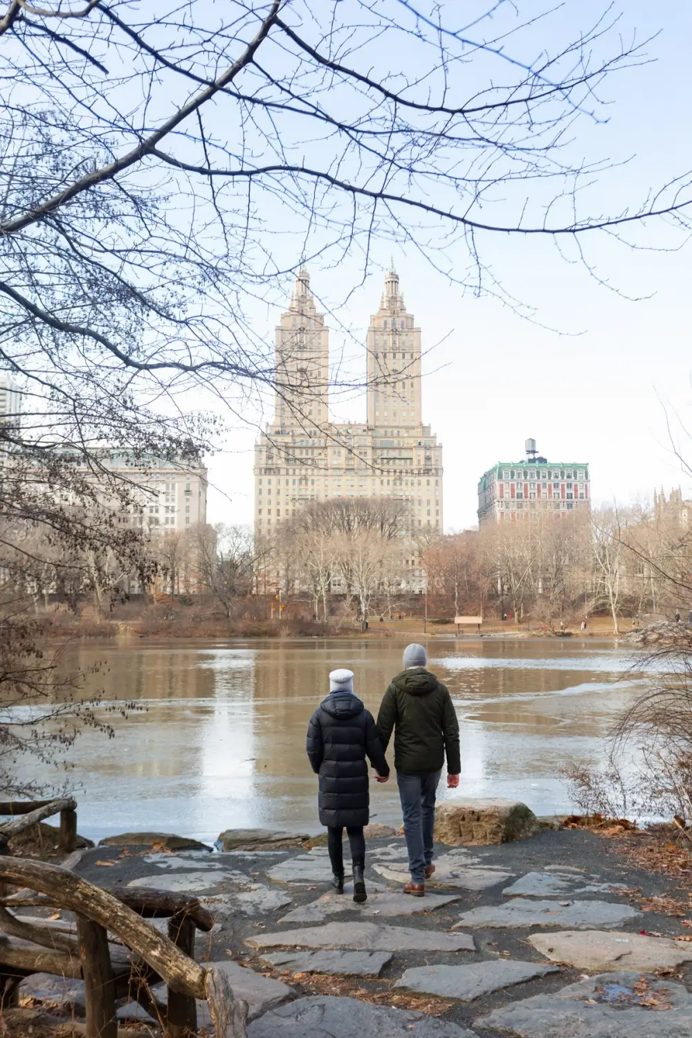 Couple holding hands by a frozen Central Park lake, a serene doula NYC moment